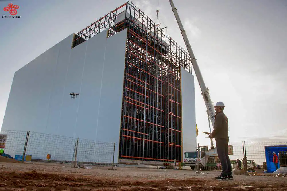 Piloto operando un dron junto a una nave en construcción